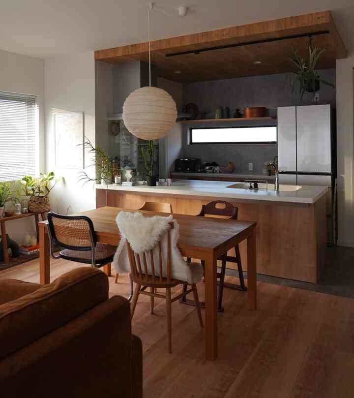 ナチュラルな木目調と白を基調としたダイニングとキッチン、食卓と椅子が配置された温かみのあるインテリア