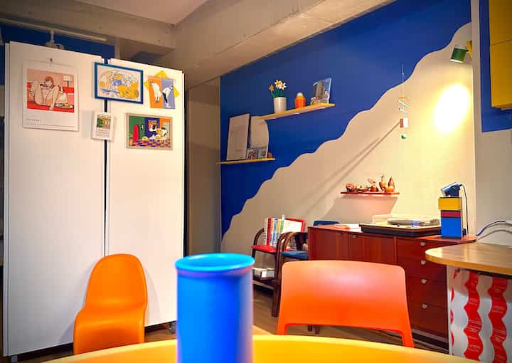 Cozy single household dining room with blue and beige tone wall featuring colorful orange and blue chairs