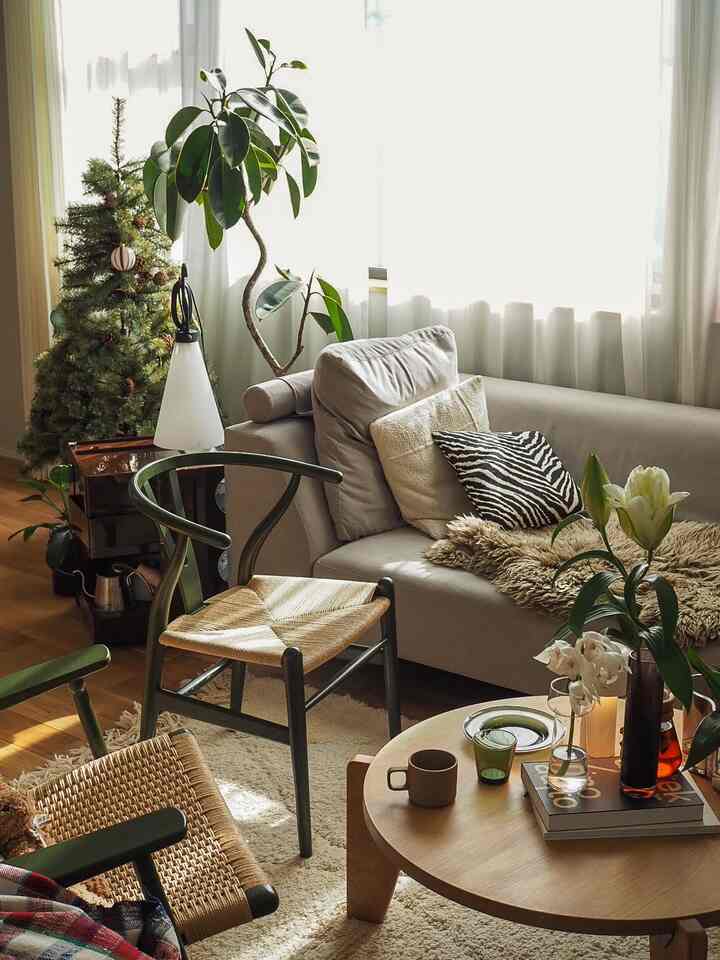 白と緑のトーンのリビング、ソファと木製ローテーブル、クリスマスツリーが温かい冬の雰囲気を演出