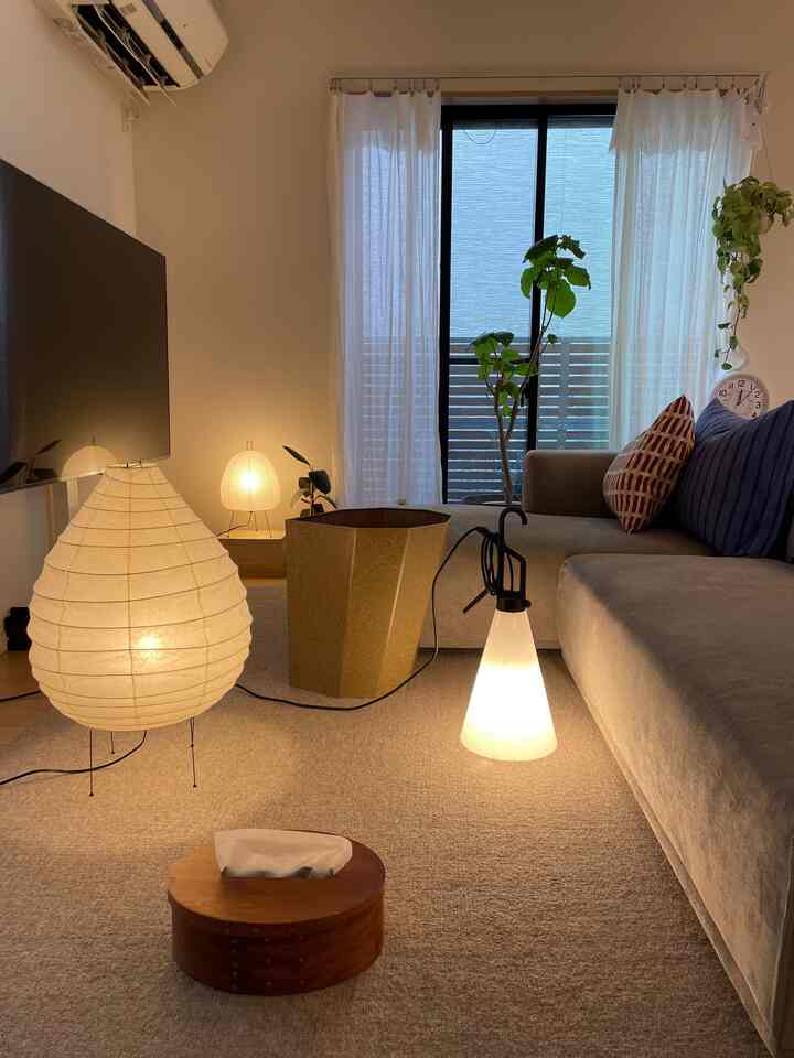 ナチュラルな色調のリビング、ベージュのソファとフロアランプ、自然素材のアクセントが調和する落ち着いた空間