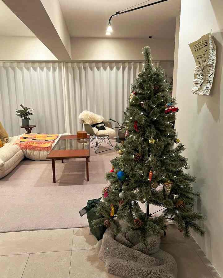 ナチュラルトーンのリビング、飾られたクリスマスツリーとソファ、コーヒーテーブルが配置された居心地の良い空間