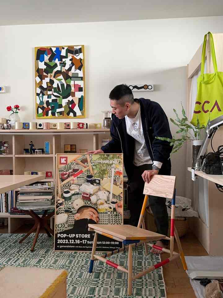 Living room with white walls and wood tone furniture, featuring a person holding a thin DIY picture frame with a poster, creating a cozy atmosphere