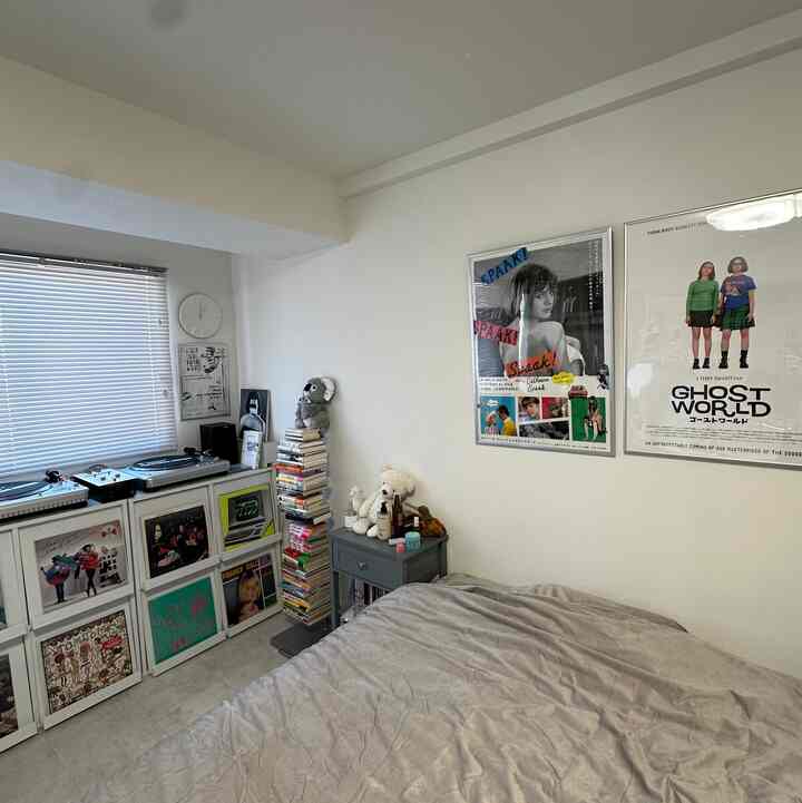 ホワイトの壁とベッド、ポスターが配置された一人暮らし向けのコンパクトな寝室のインテリア