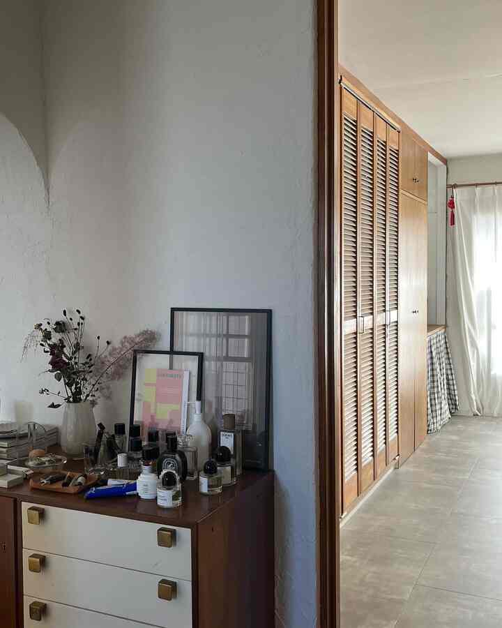 ナチュラルな木目調と白い壁の狭い廊下、ビルトインクローゼットとチェストが配置された落ち着いたインテリア