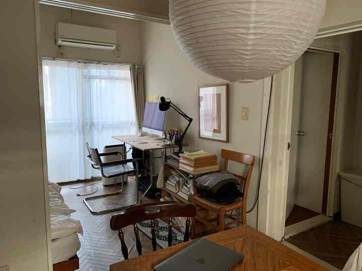 Natural-toned studio apartment dining room featuring a computer desk and dining chairs in a cozy home office setup