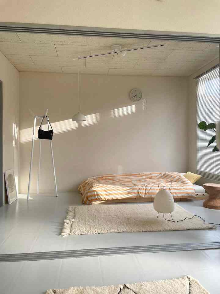 Bright beige and white toned bedroom featuring a simple coat rack and low bed creating a cozy space
