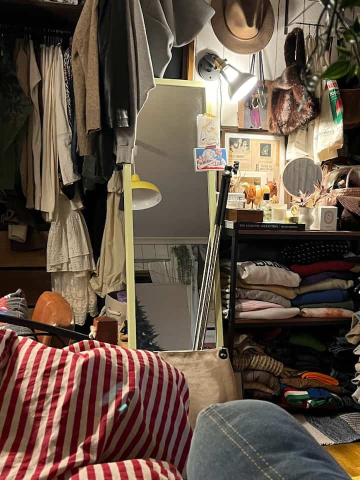 Cozy dressing room with red striped duvet cover and closet filled with various clothes and accessories, showcasing organized space