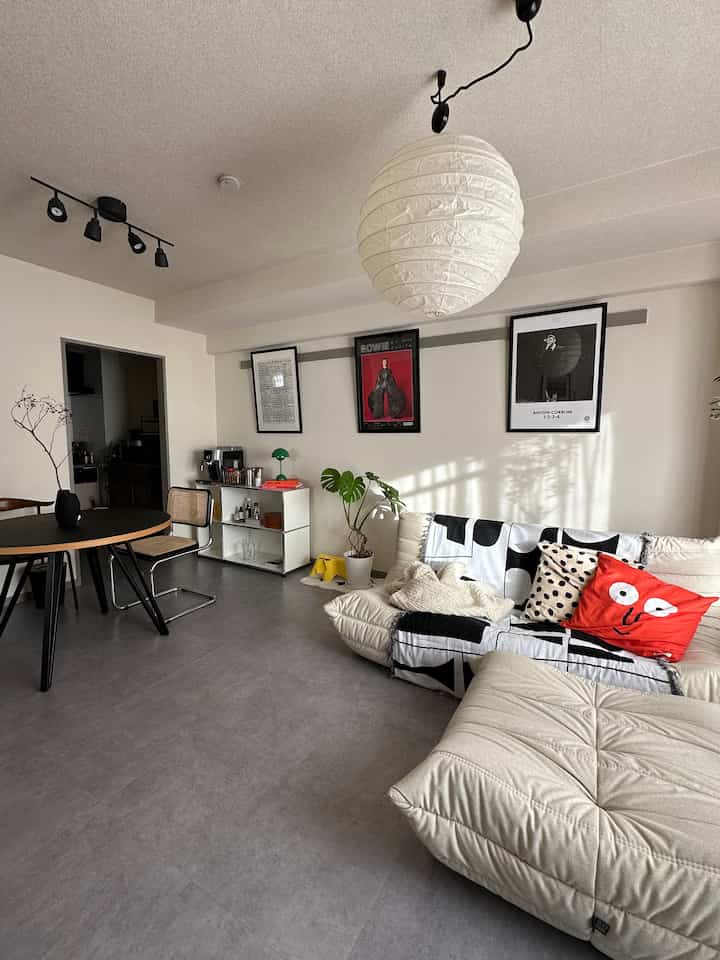 ホワイトとブラックのトーンでまとめられたミッドセンチュリーモダンのリビング、クリーム色のソファと丸いダイニングテーブルが配置された印象的な空間