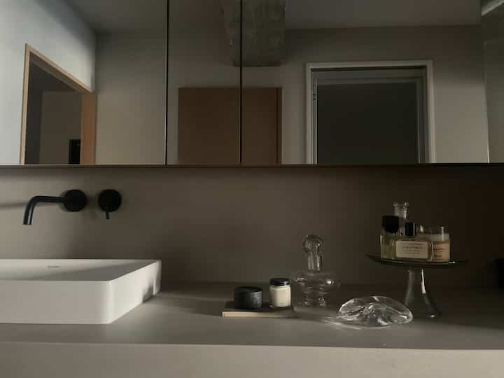 Gray and white toned bathroom featuring a white sink and transparent glass objets with a calm modern atmosphere