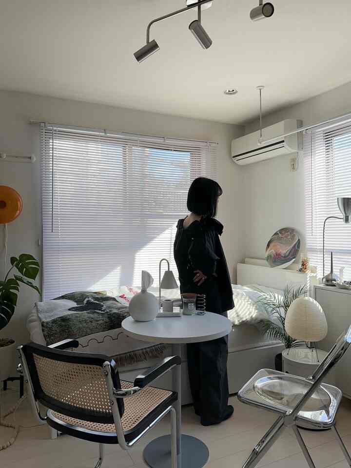 白とシルバー調の小さな部屋、ベッドと丸テーブル、2脚の椅子が配置されたシンプルでナチュラルモダンな印象的な空間