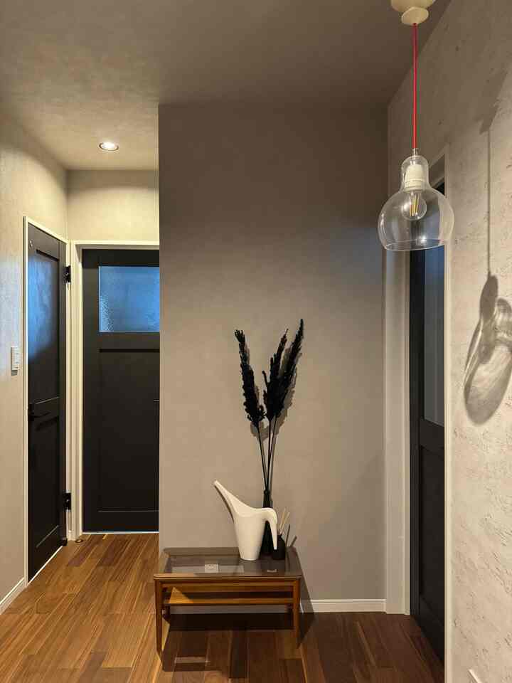 Natural color walls and wood tone flooring entrance featuring wooden side table with white watering can and minimal decorations