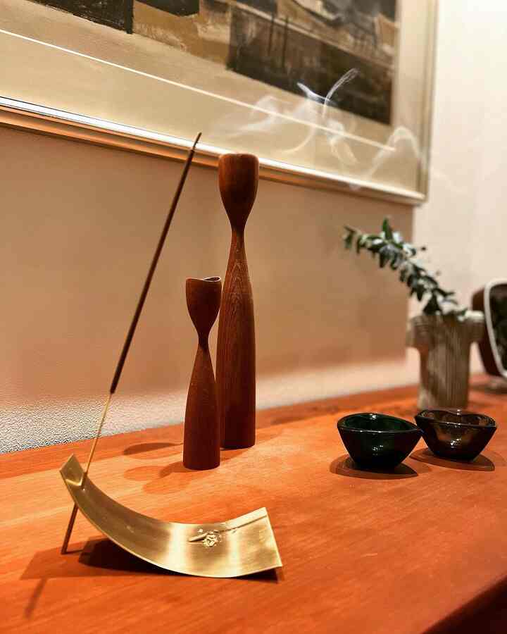 温かみのある木目調の空間に真鍮のお香立てと木製のオブジェが配置された印象的なホテルライクインテリア