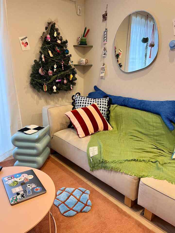 Natural small living room with a beige sofa, colorful cushions, and a handmade wall-mounted Christmas tree decor