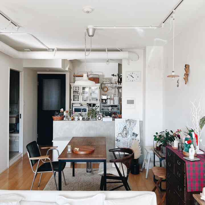 ホワイトとブラウンの色調のリビング兼ダイニングルーム、木製のダイニングテーブルと椅子、ペンダントライトが配置されたナチュラルな印象の空間