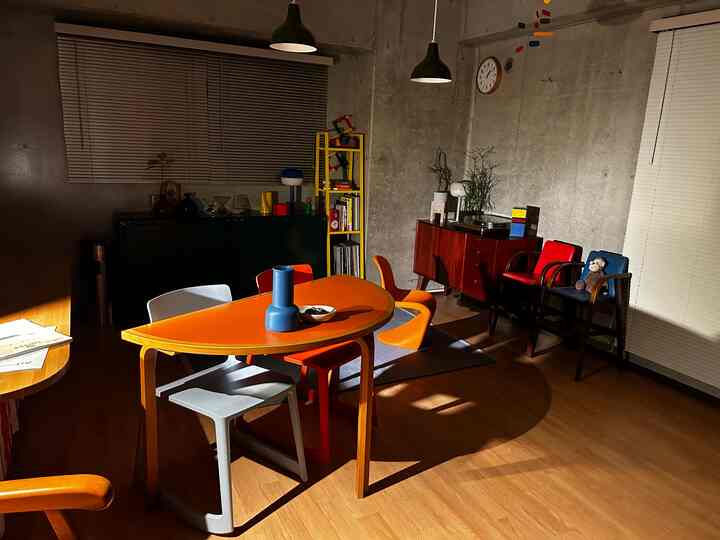 温かみのある木目調床と鮮やかなオレンジのダイニングテーブルが配置された北欧風ダイニングルーム