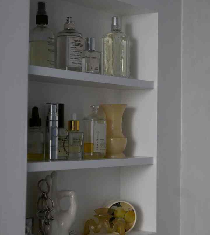 White-toned niche space featuring cosmetics and objets arranged neatly in a clean bathroom storage area