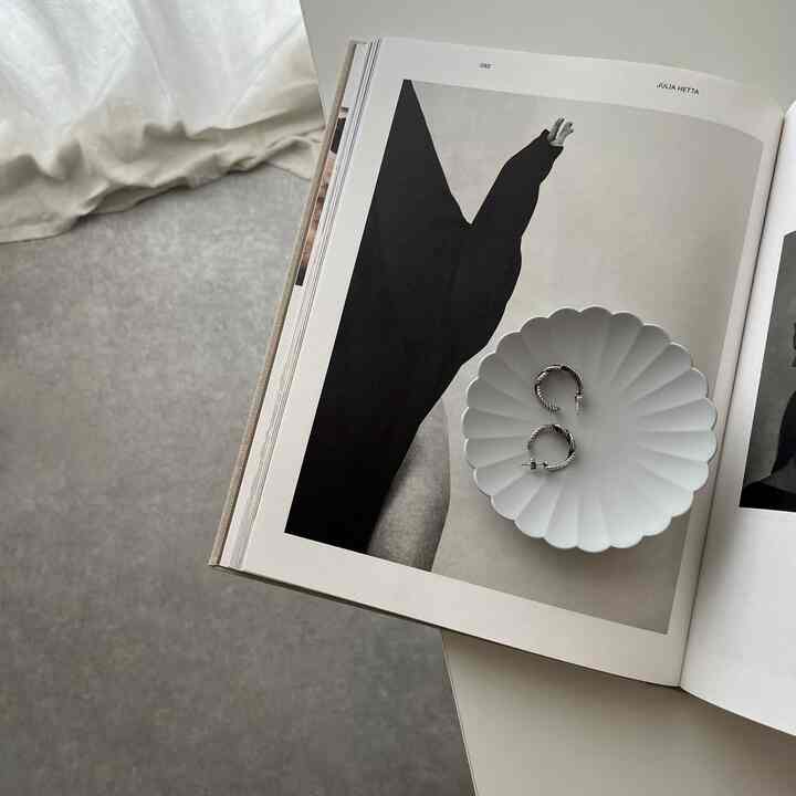 Simple and natural studio apartment with white and gray tones, featuring a plate with jewelry on a dining table