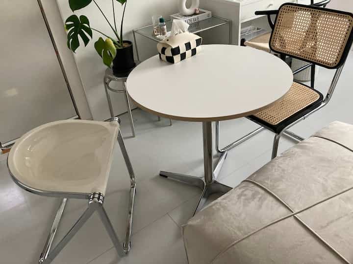 White and silver-toned mid-century modern small dining space featuring foldable chairs and a round table