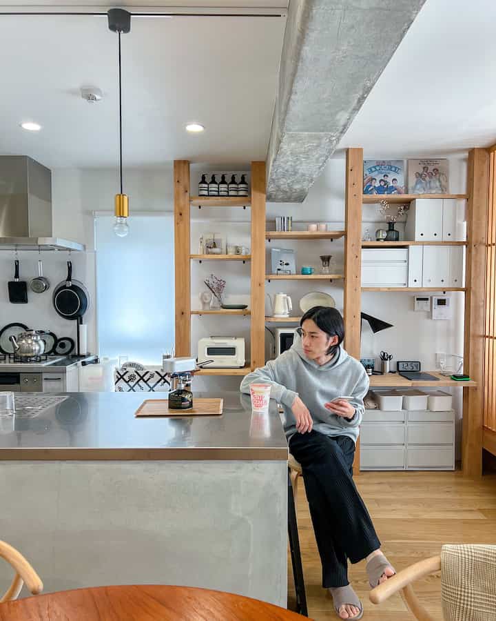 白と木目調が基調のキッチン、シンプルで整ったデザインに一人が座っている印象的な空間
