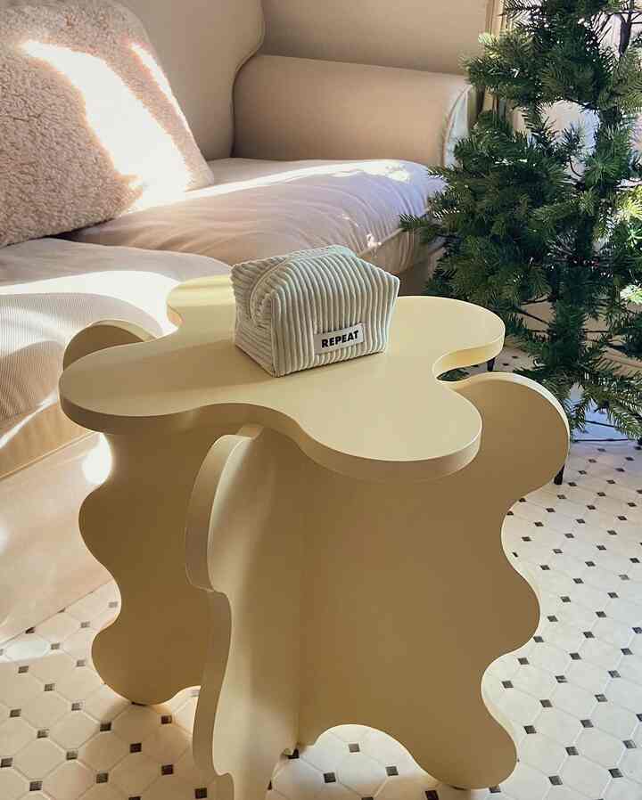 柔らかいベージュのトーンのリビング、ベージュのソファと波状のサイドテーブルが配置された雰囲気のあるインテリア