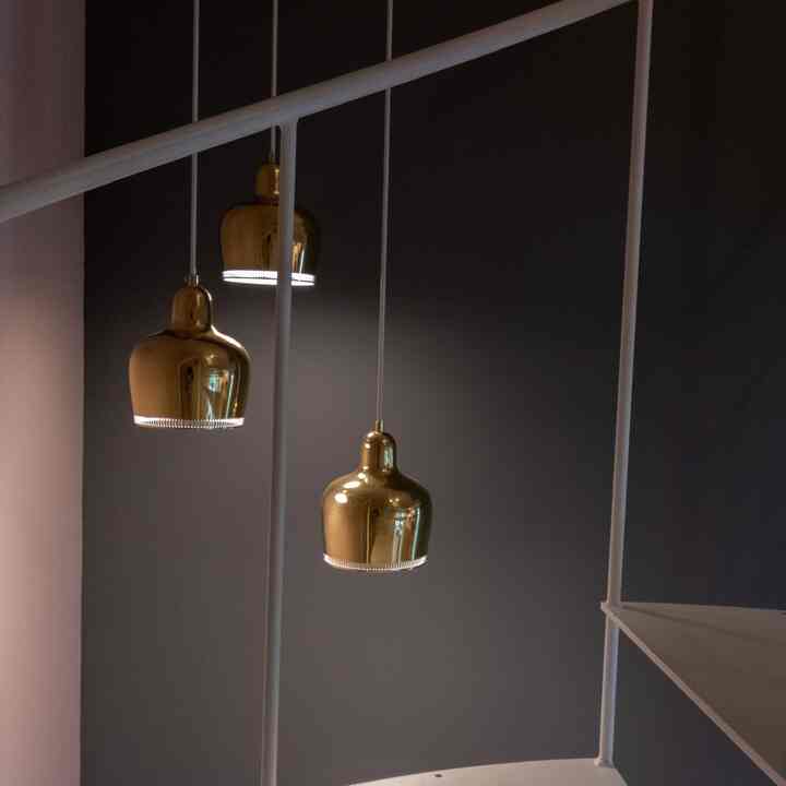 ゴールドのペンダントライトが吊るされた白い鉄骨の螺旋階段、モダンでシンプルなインテリア