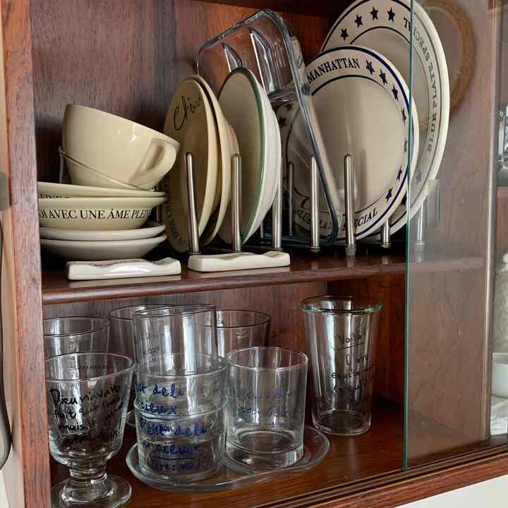 温かみのある木目調のキッチンキャビネットに、様々な皿とグラスが整然と並べられた雰囲気のあるインテリア