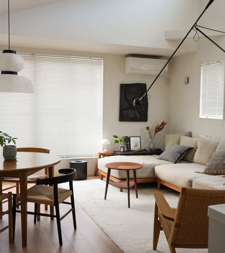 Natural color and wood tone living and dining room featuring a 3-person sofa and round dining table, creating a cozy atmosphere