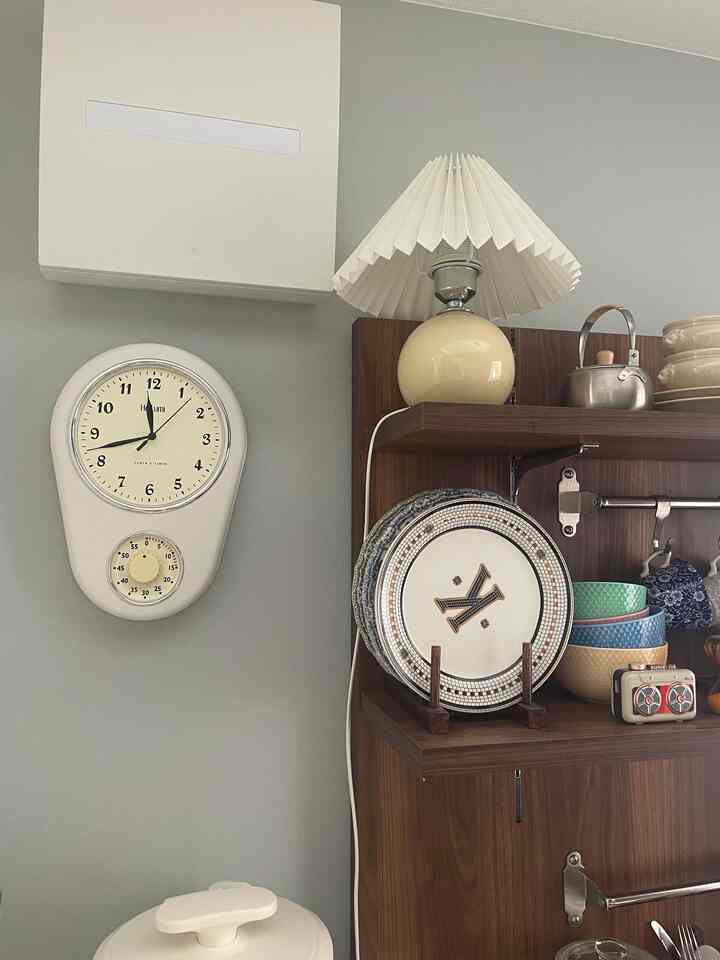 アイボリー色の時計とブラウンの木製棚が配置された温かみのあるキッチンの印象的なインテリア