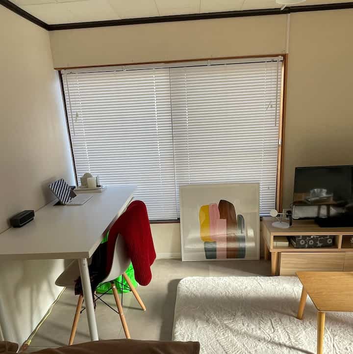 Bright living room in white and wood tones featuring a neat desk and TV stand with a simple atmosphere