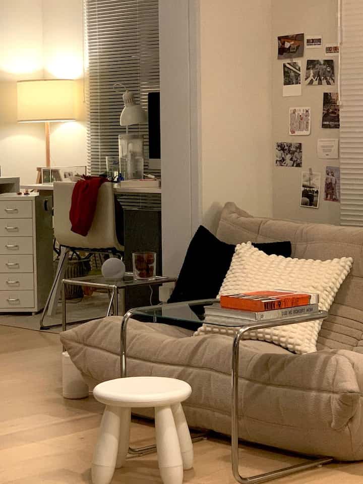 Beige-toned living room featuring a Roset Togo sofa, white stool, and side table arranged in a cozy setting