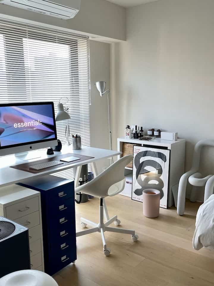 Modern bedroom home office with white and wood tones, featuring white desk and chair in a clean space