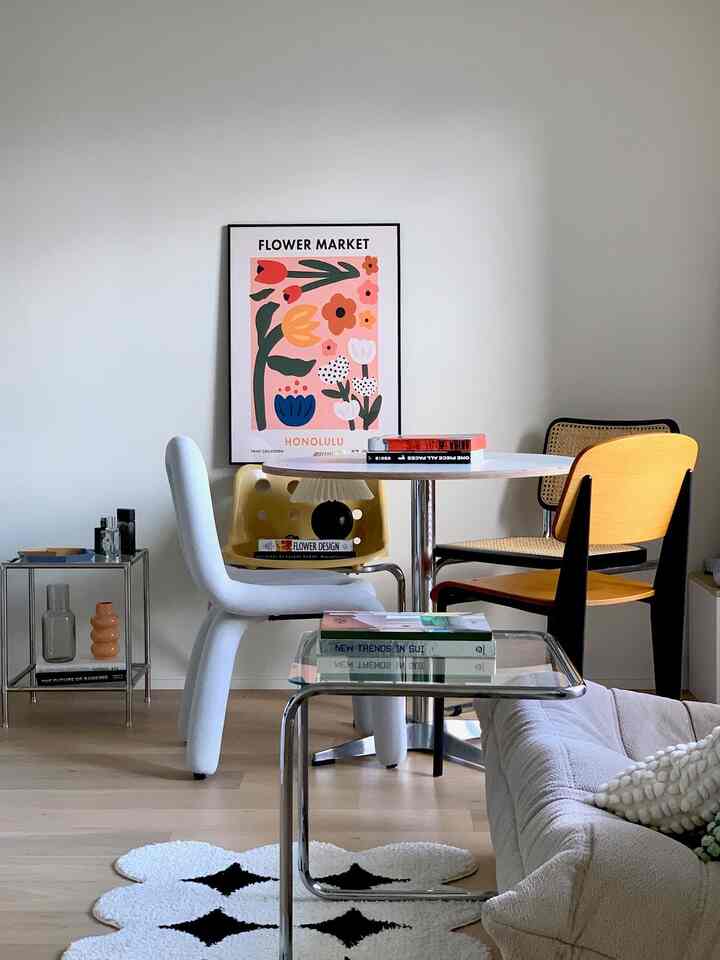 Natural modern dining room with white walls and warm brown wood floor, featuring a variety of dining chairs around a round table