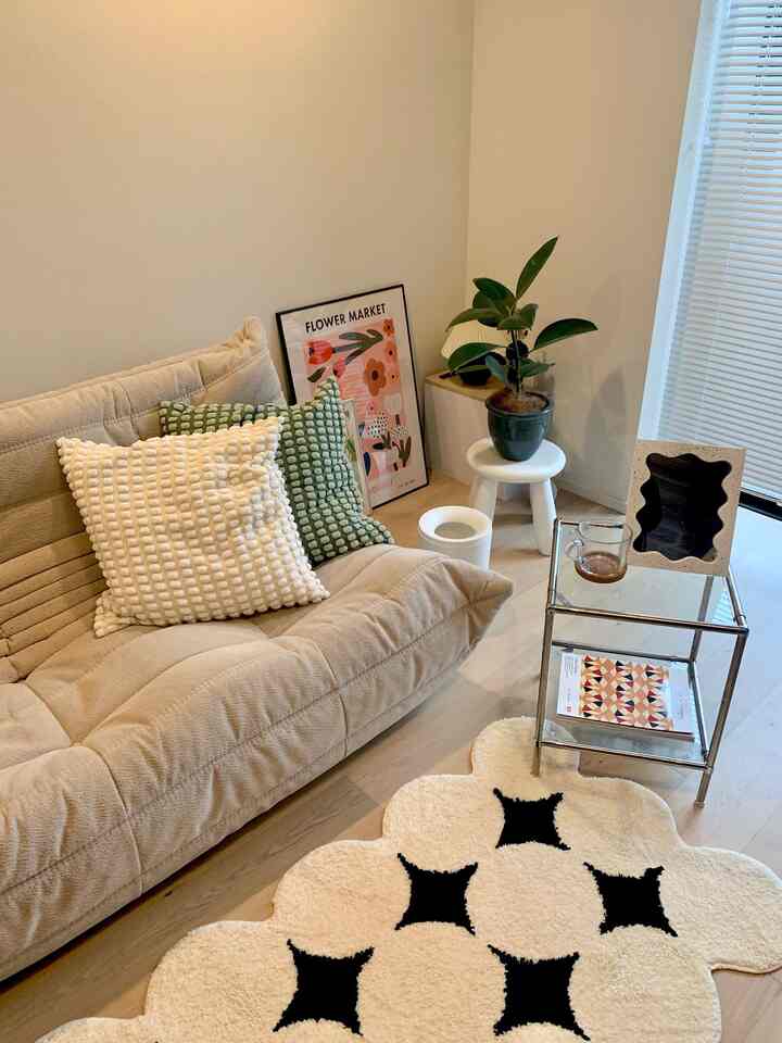 ベージュの色調のリビング、中央に居心地の良いソファとカラフルなクッション、特徴的な柄のラグが配された、自然でモダンな雰囲気のインテリア