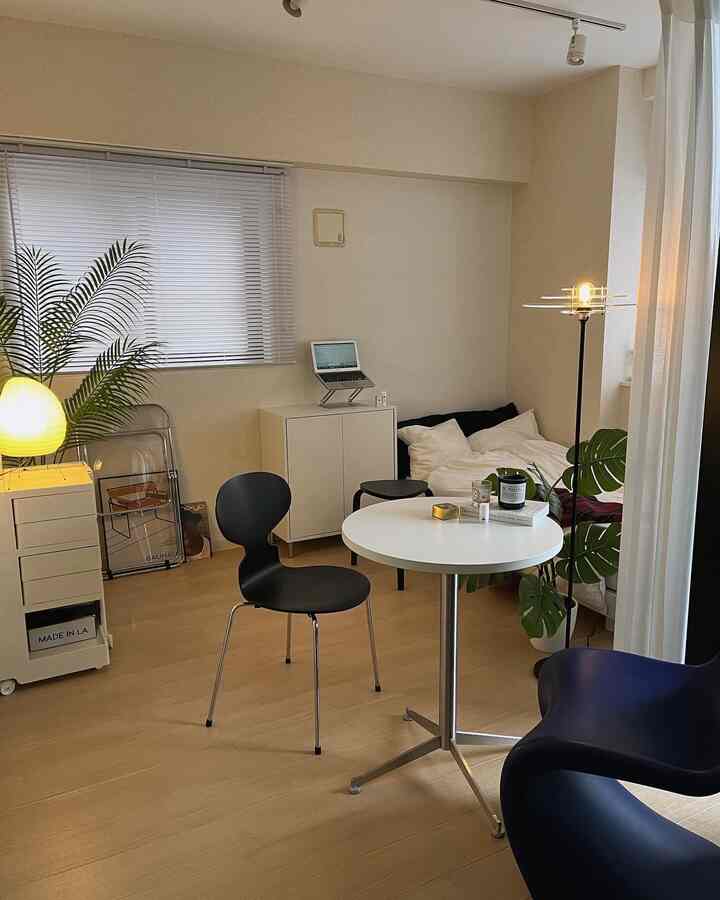 白と茶色のトーンが特徴の1人暮らし用ワンルーム、ナチュラルモダンスタイルの丸テーブルとモダン家具が配置された空間