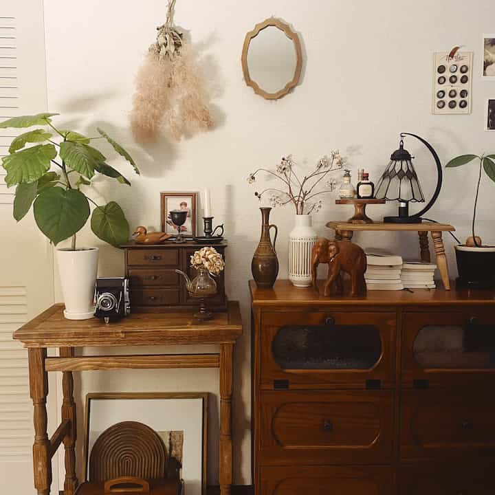 ナチュラルブラウンのヴィンテージ風リビング、クラシックな木製家具と植物が配置された雰囲気のある空間