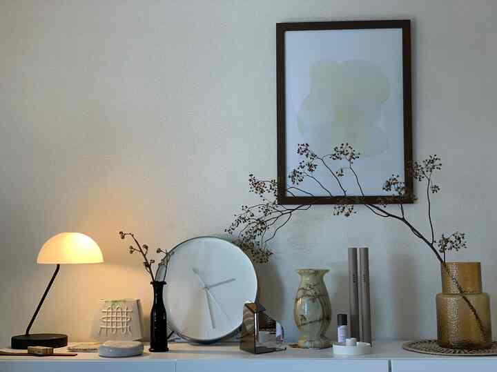 ベージュとブラウンの色調の空間、モダンな小物と大きな白い壁掛け時計が置かれたシンプルでナチュラルなインテリア