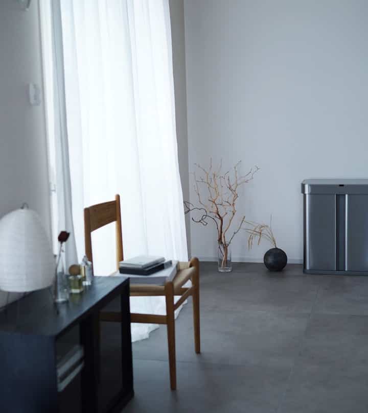 Gray-toned dining room featuring wooden dining chair and lamp, creating a simple and inorganic atmosphere