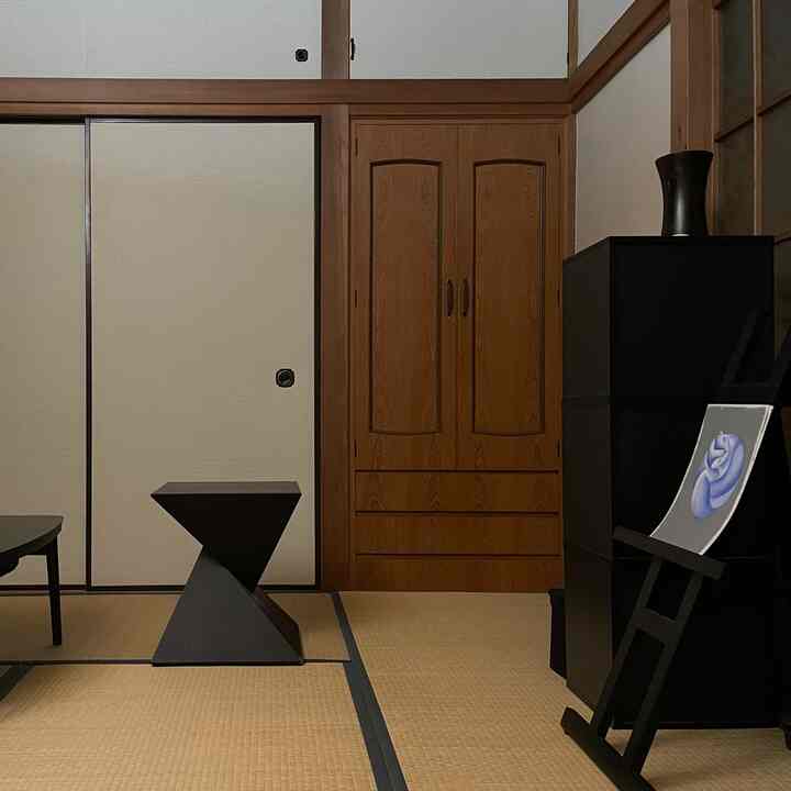 黒い家具と木目調の壁が調和した伝統的な和モダンの6畳畳の部屋