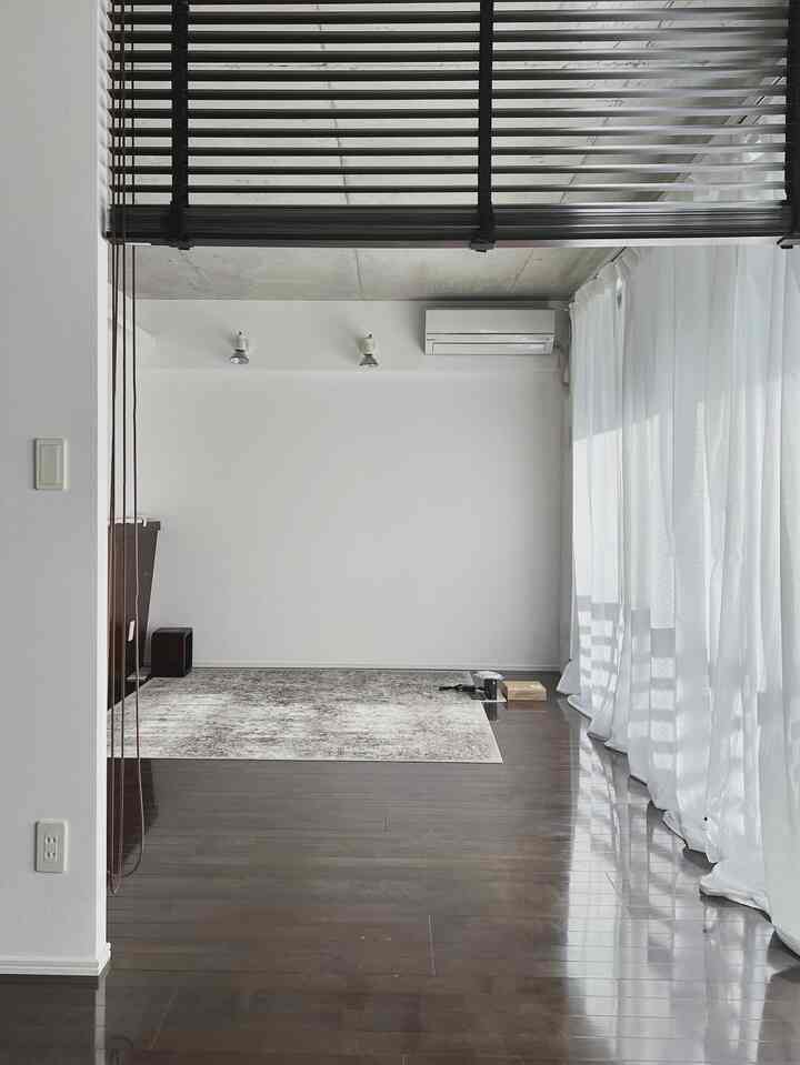 白いカーテンとグレーのラグが配置された一人暮らし向け1LDKリビング、清潔感と自然な雰囲気のあるインテリア