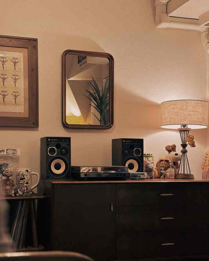 ブラウンとベージュの色調のリビング、ヴィンテージのキャビネットとテーブルランプ、壁掛け鏡が温かみのある雰囲気を作る空間