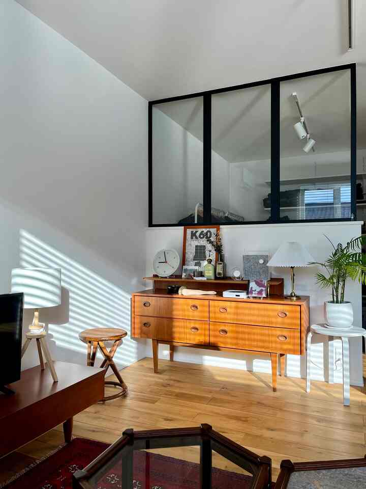 白い壁と木目調のサイドボードが配置されたヴィンテージ風のリビング空間