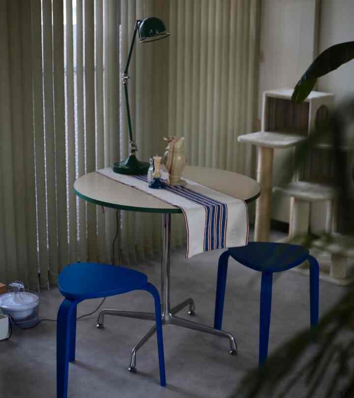 ナチュラルカラーの室内、丸テーブルと青いスツール2脚が配置された印象的な空間