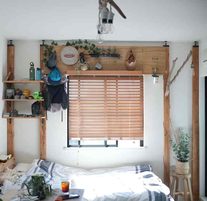 ブラウンの木製ブラインドとナチュラルな木製フレームが調和するワンルーム寝室、実用的な収納アイデアが際立つ雰囲気のあるインテリア