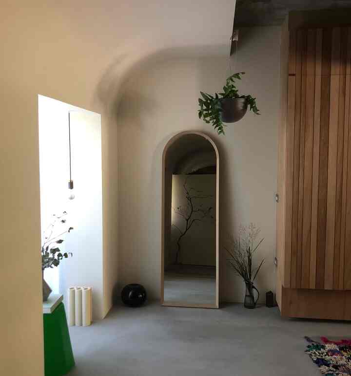 Natural tone entrance featuring an Art Deco arched ceiling and tall mirror in a clean minimalist space