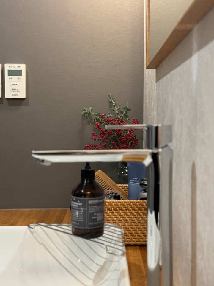 ナチュラルなウッドトーンとベージュの壁が調和した化粧台スペース、赤い実と植物が配置された縦長の部屋