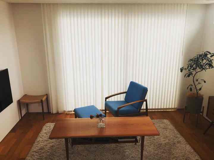 Natural color-toned living room for two featuring a blue armchair and ottoman, with wood accents and simple design