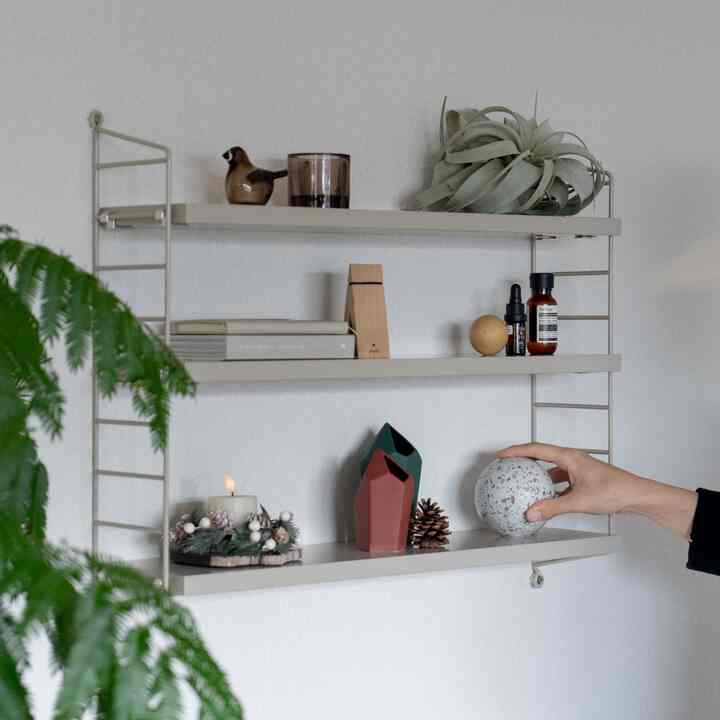 Natural toned dining room wall with mounted shelves displaying various decorative items in a cozy corner
