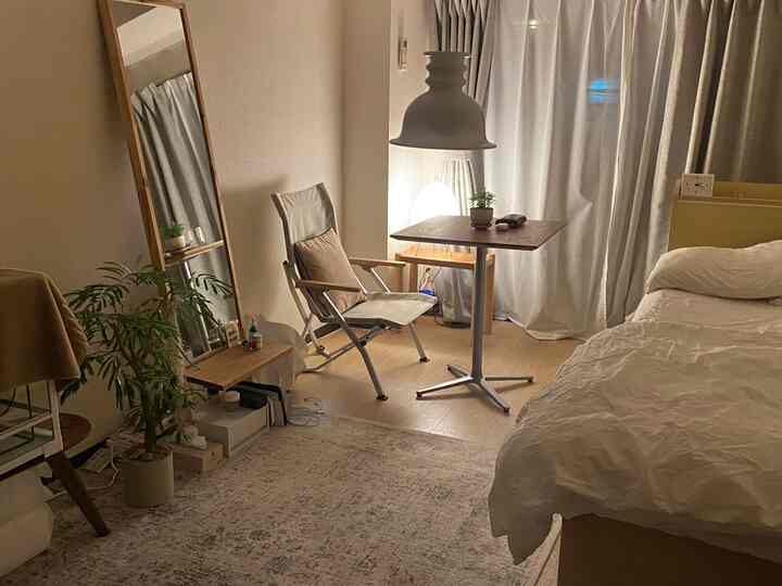 Cozy bedroom in warm beige and white tones featuring natural wood furniture and floor lamp creating a calming atmosphere