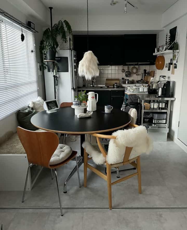 ブラックとホワイトの色調のダイニング、木製チェアとペンダントライトが調和したコンパクトでナチュラルなキッチンスペース