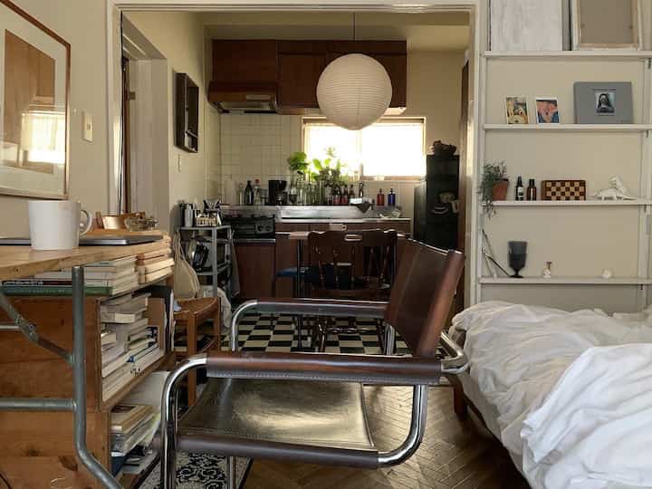 Natural-toned studio apartment featuring a combined kitchen and bedroom with multifunctional furniture and bright lighting, creating a cozy atmosphere